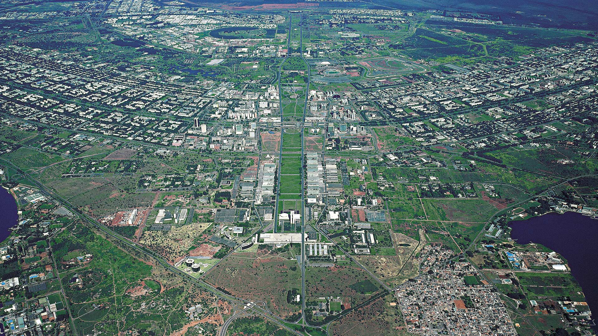Fotografia aérea de João Facó do centro de Brasília mostrando a estrutura das Asas Sul e Norte com evidência do verde distribuído entre as construções de prédios.