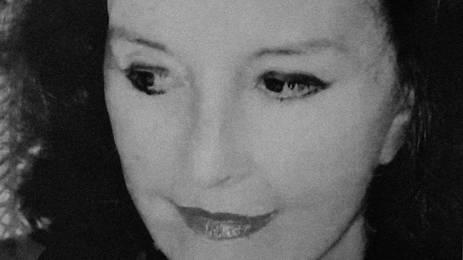 Fotografia de rosto da artista plástica Marianne Peretti em preto e branco. Ela é branca, tem cabelos pretos que estão soltos, sobrancelhas pretas e arqueadas, olhos pretos pintados com sombra, delineador e rímel, nariz fino e boca pequena pintada de batom. Mostra um olhar para a lateral esquerda e tem um ar sereno e leve.  